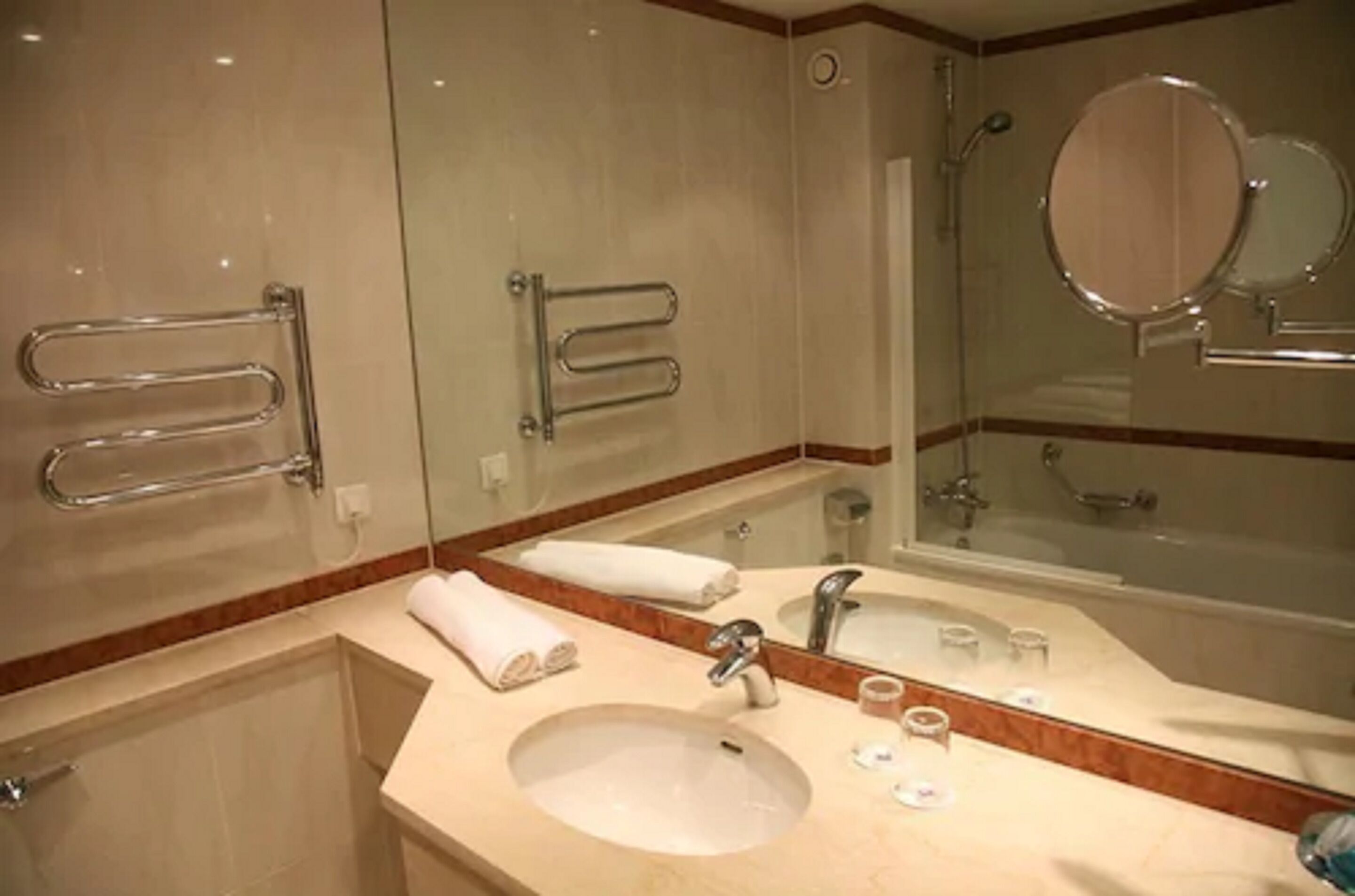 Un baño con lavamanos, espejo, toallero y ducha.
