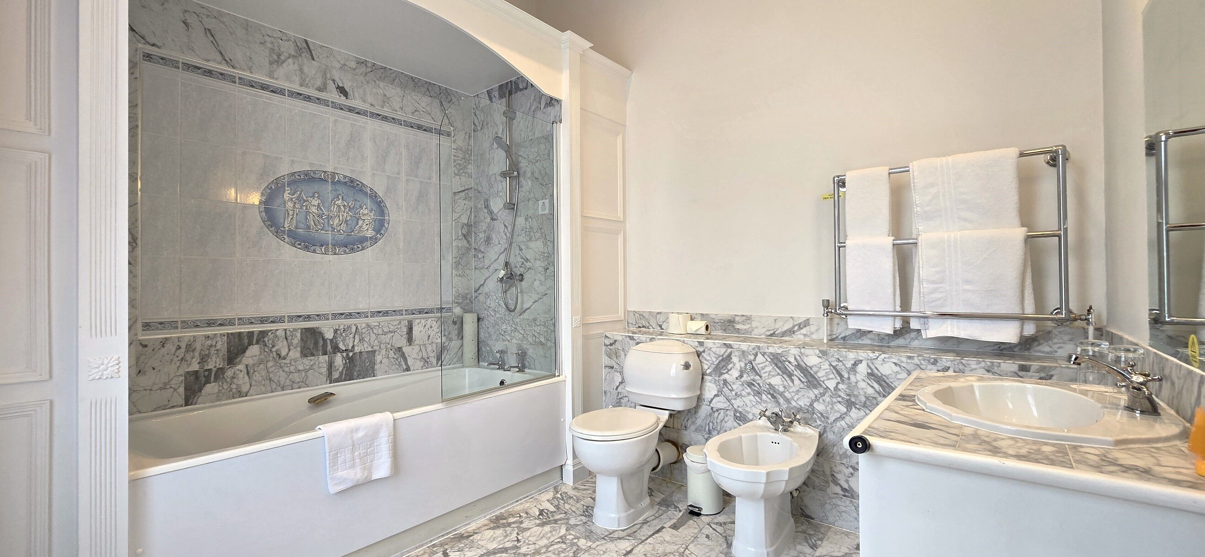 A bathroom with a glass-enclosed shower, a bathtub, two toilets, a bidet, and two sinks.