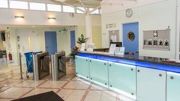 A reception area with a blue door, a reception desk, a bulletin board, and a clock on the wall.