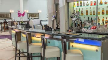 Un espace bar comprenant un comptoir, des tabourets de bar et une variété de bouteilles et de verres.