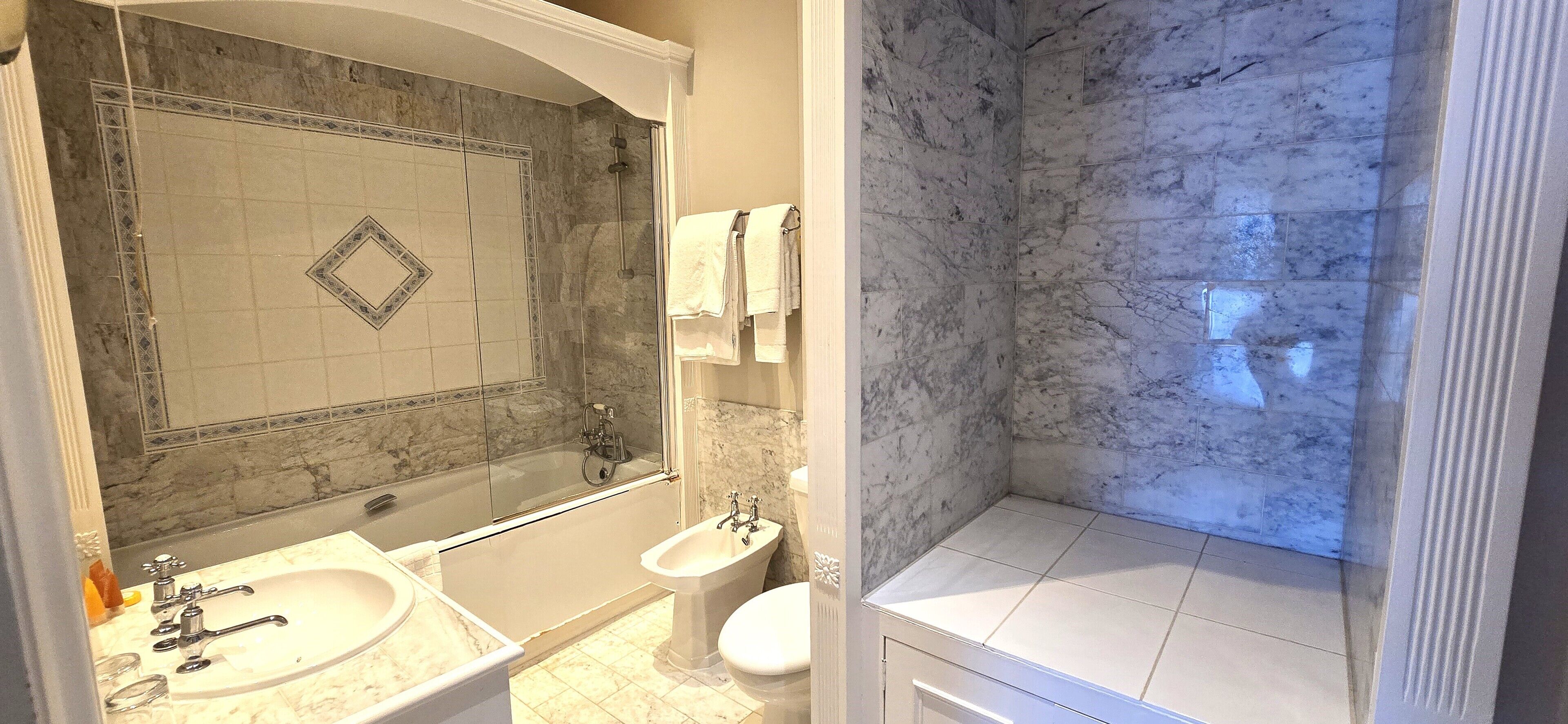 Un baño con bañera, lavamanos, bidé y zona de ducha.