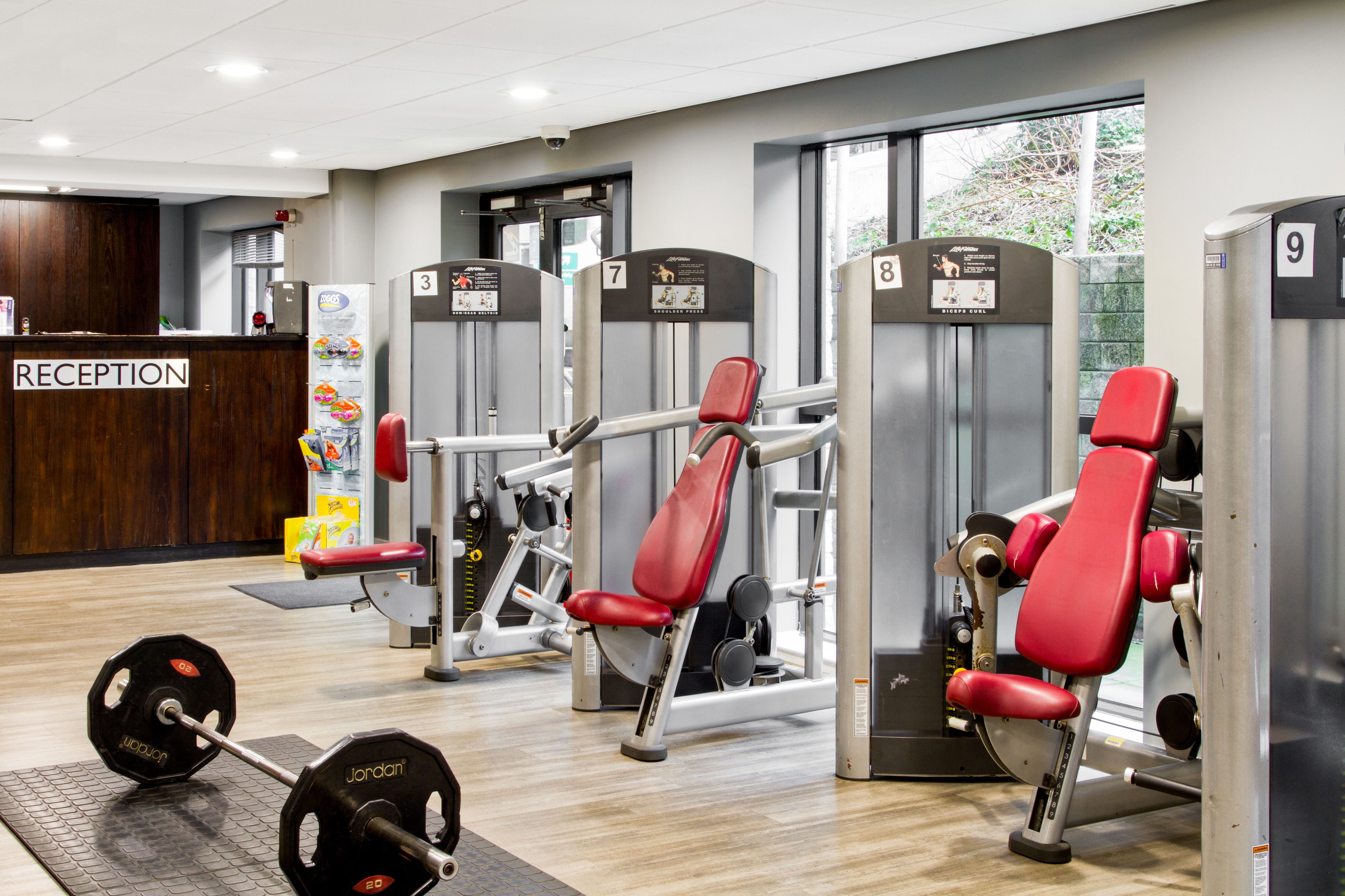 A gym with weightlifting equipment, a reception desk, and numbered lockers.