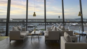 A modern hotel room with large windows offering a view of an airport and control tower.