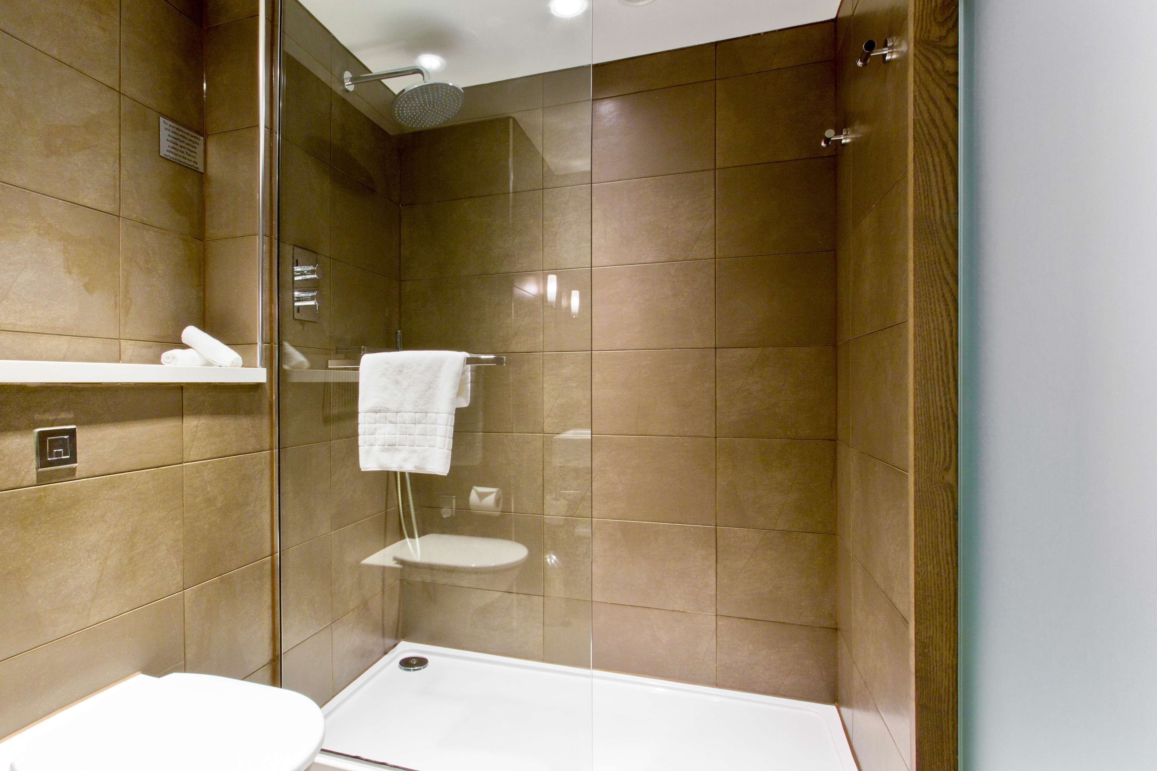 A modern bathroom with a glass-enclosed shower, a white toilet, and a towel rack.