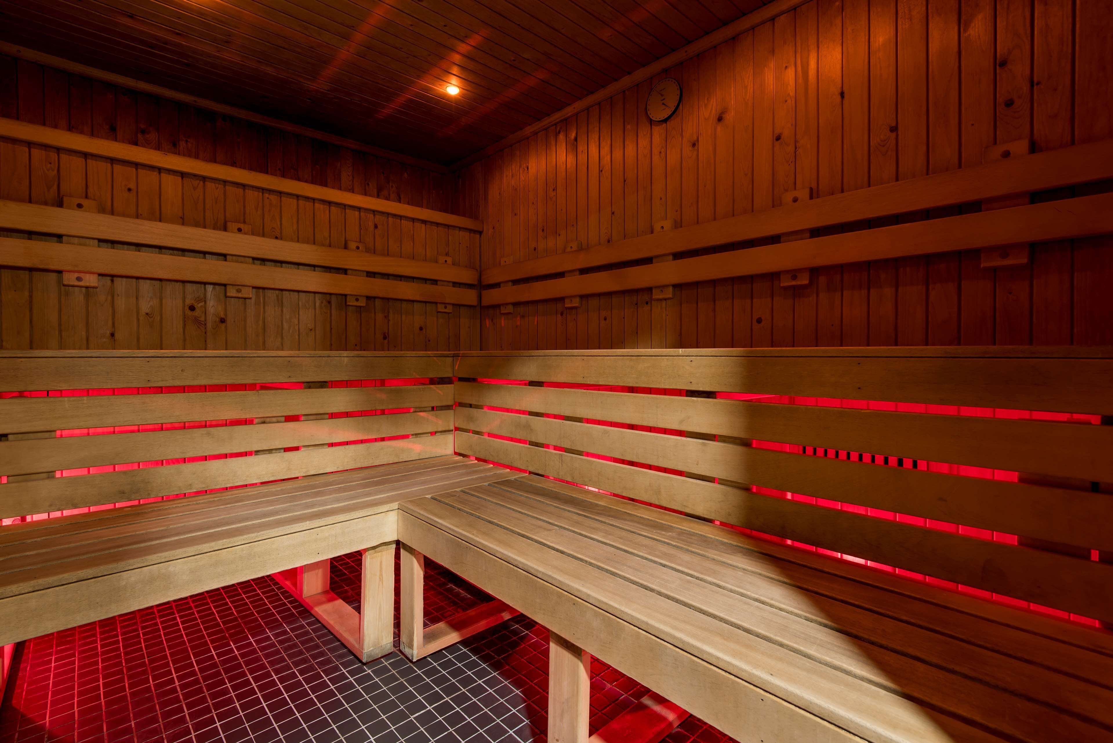 Una sauna con bancos de madera e iluminación roja.