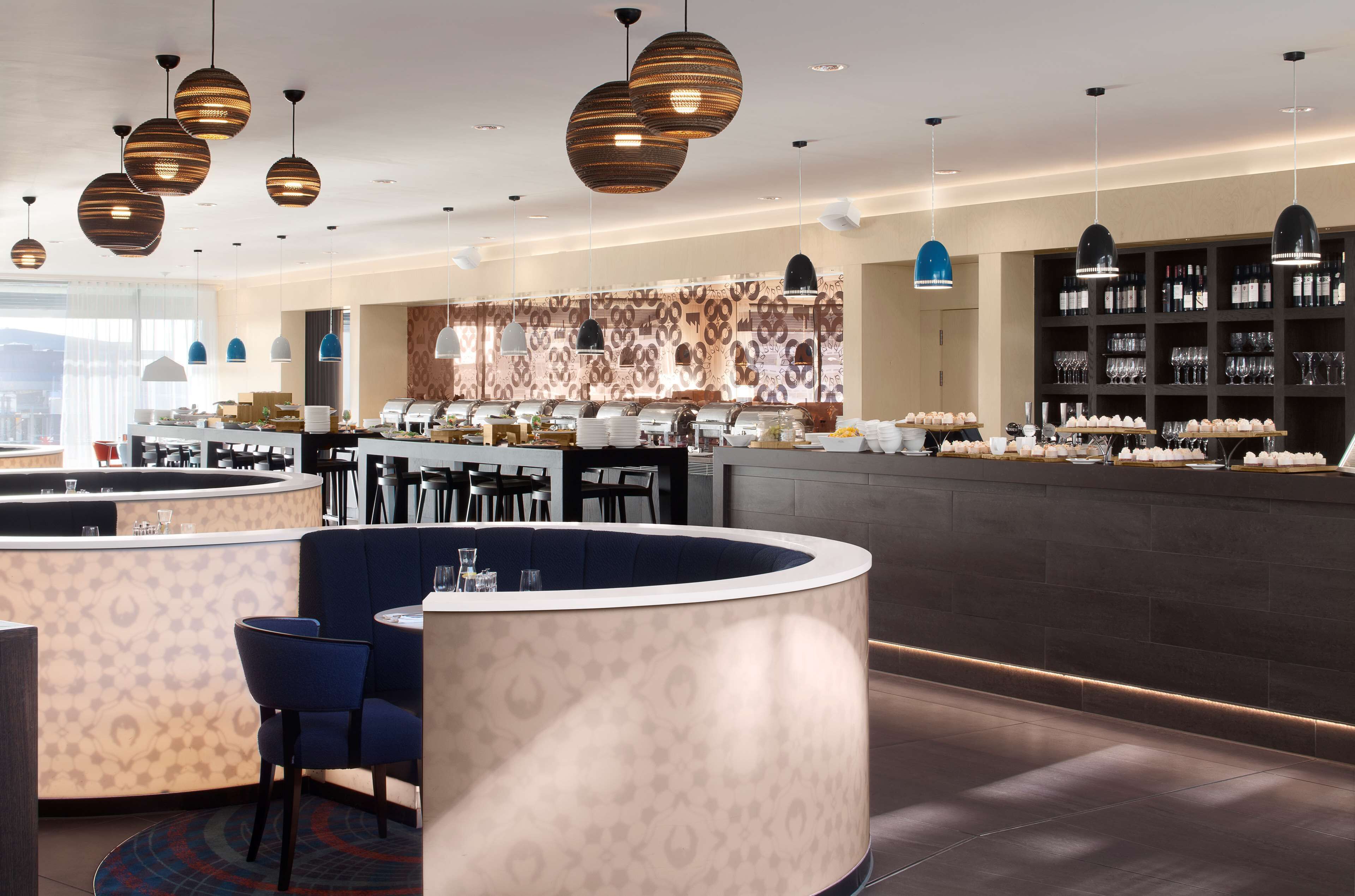 Un restaurante moderno con mostrador central, zona de estar y exposición de vinos.
