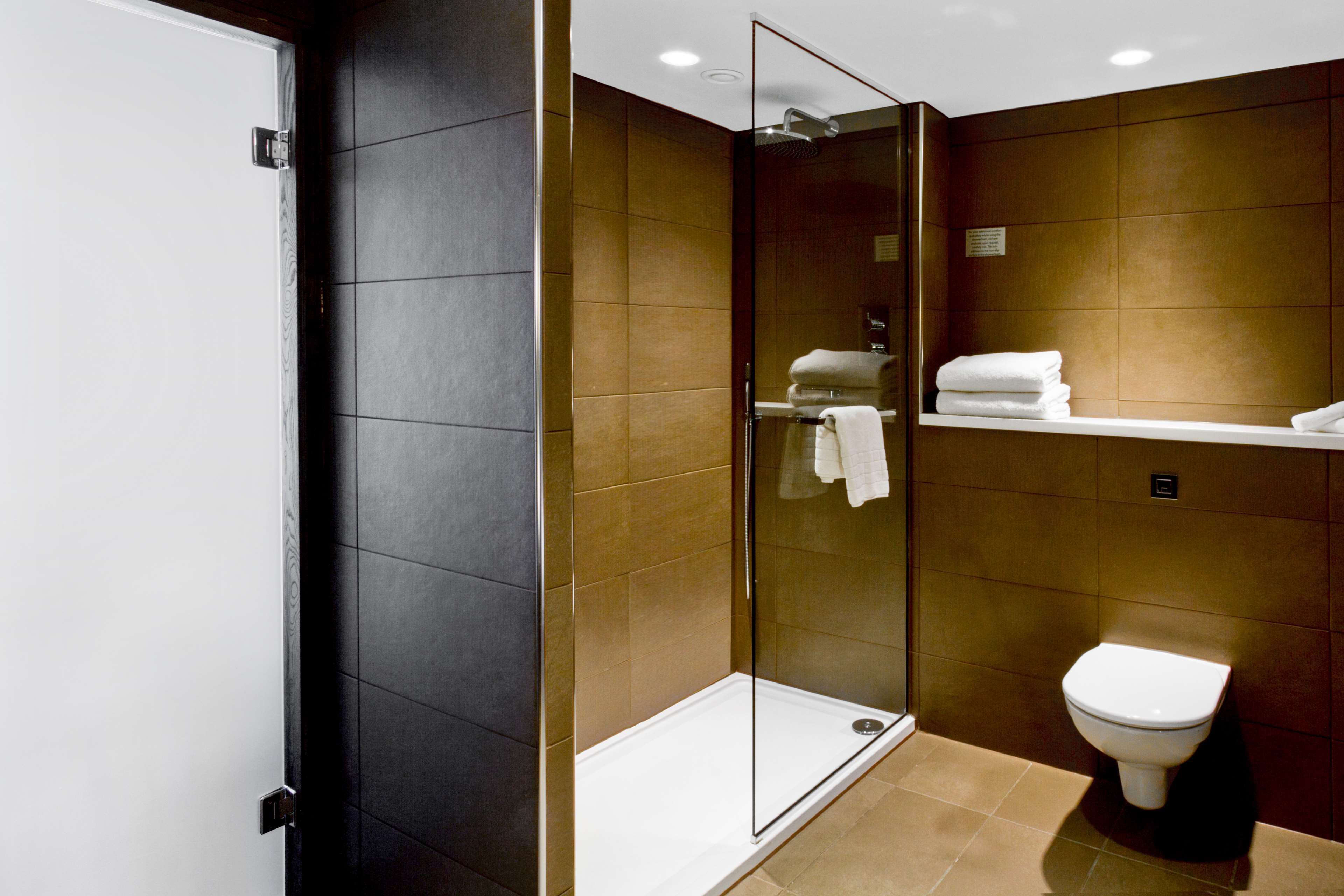 Un baño moderno con ducha envuelta en vidrio, inodoro y perchero para toallas.