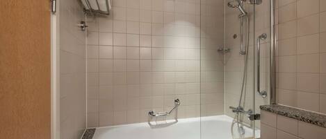 A modern bathroom with a glass-enclosed shower, a white bathtub, and a towel rack.
