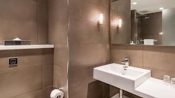 Un baño moderno con un lavabo blanco, un espejo y una ducha.