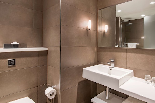 A modern bathroom with a white sink, a mirror, and a shower.