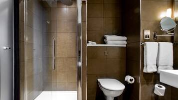 A modern bathroom with a glass-enclosed shower, a toilet, and a sink with a mirror.
