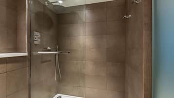 A modern shower with a glass door, a handheld showerhead, and a wall-mounted towel rack.