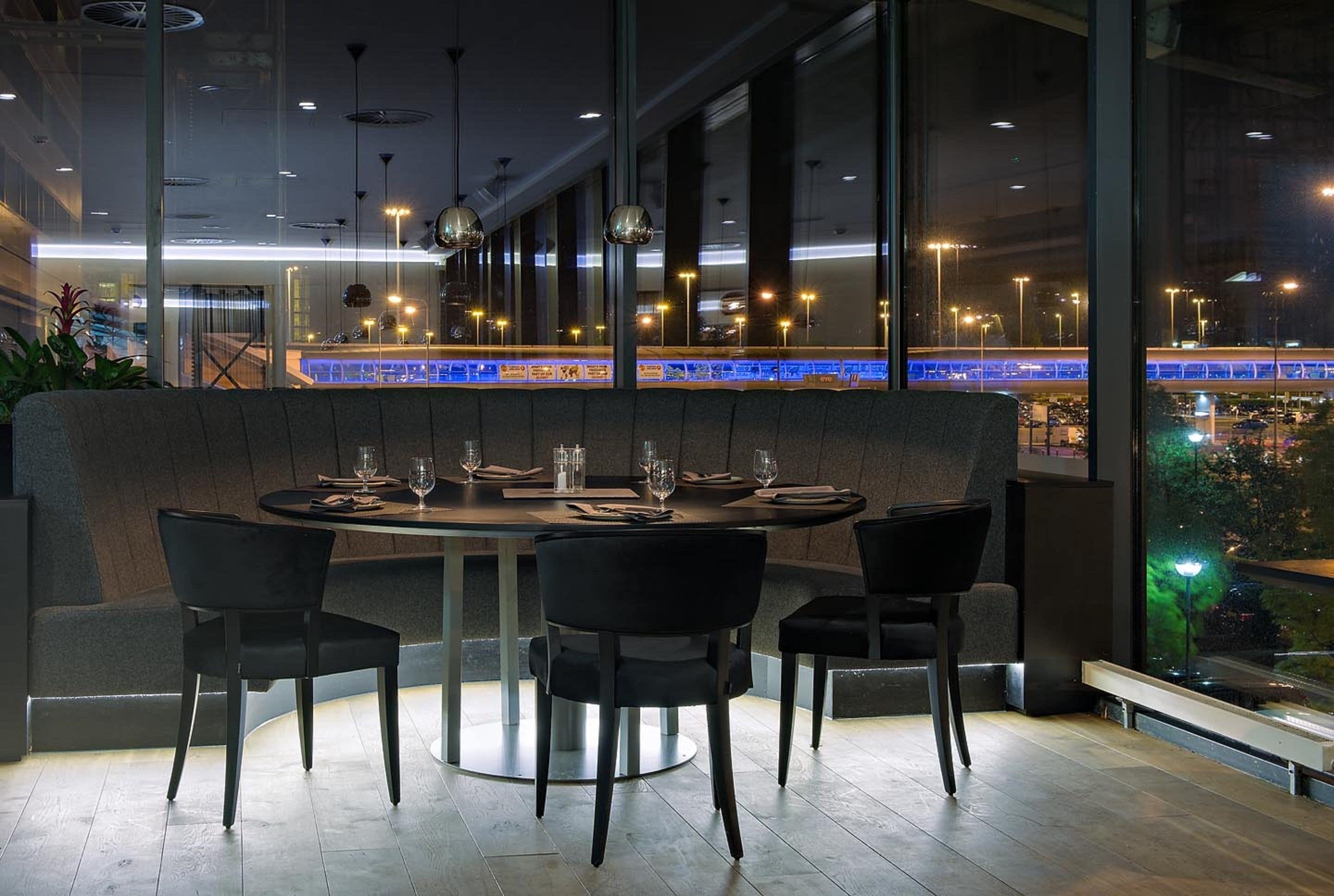 A modern restaurant with a large window overlooking a cityscape.