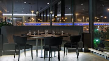 A modern restaurant with a large window overlooking a cityscape.