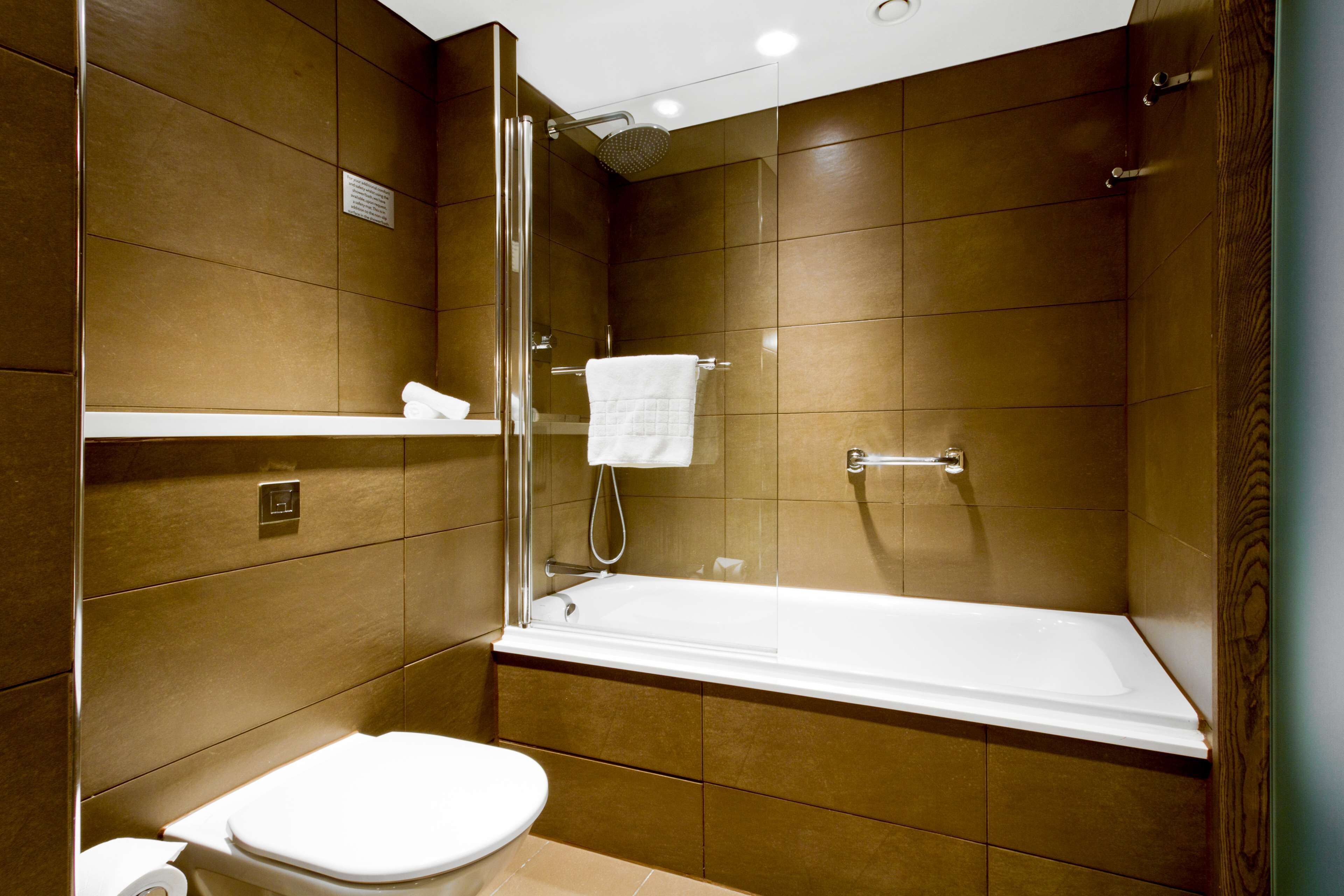 A modern bathroom with a bathtub, toilet, and shower.