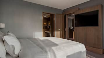A hotel room with a large bed, a wooden wardrobe, and a television mounted on the wall.