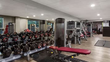 Un gimnasio con equipamiento de levantamiento de pesas, una banca y un muro de espejos.