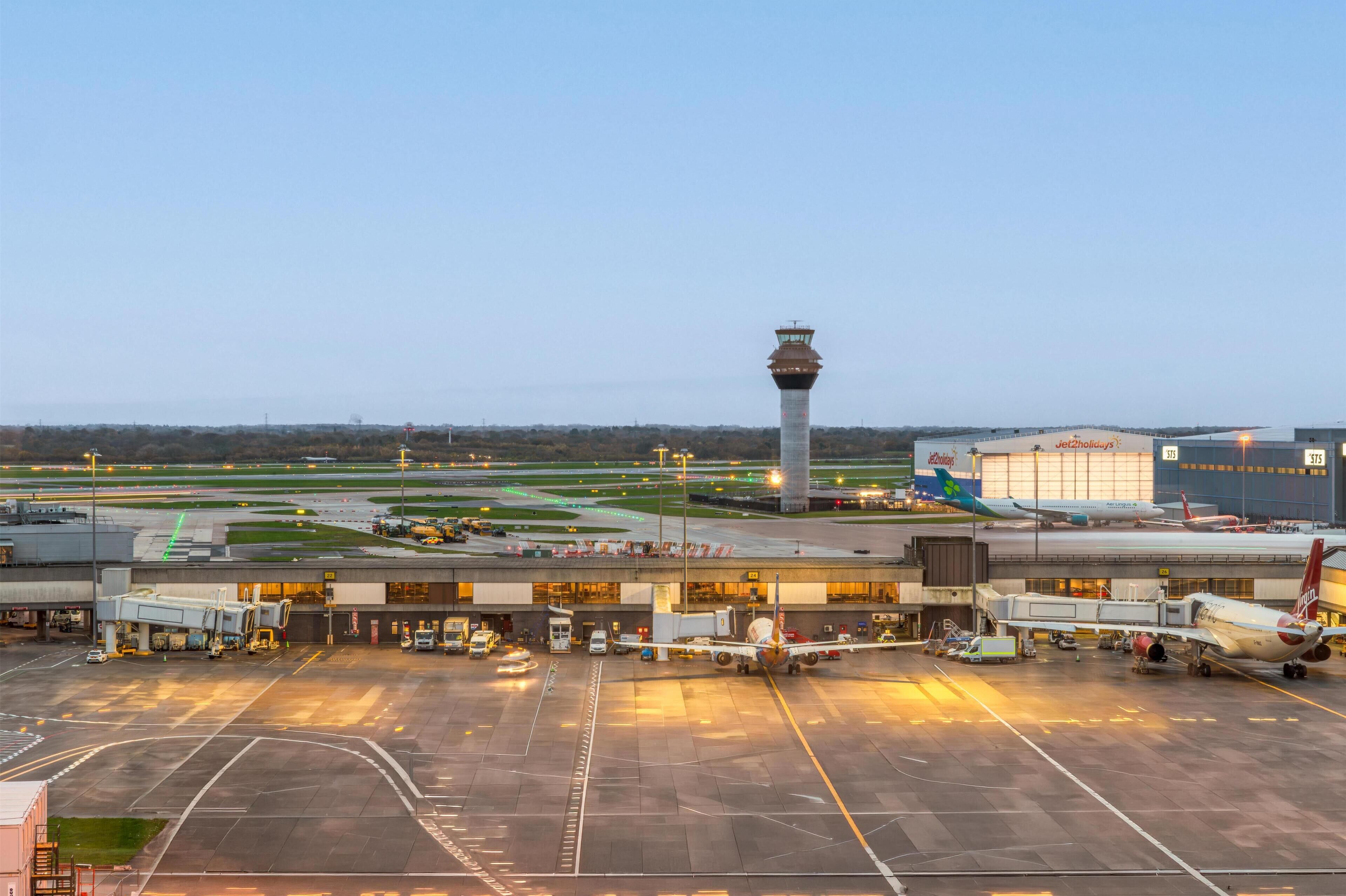 An airport terminal with a control tower, jet bridges, and parked airplanes.