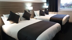 Two double beds with black and white bedding, a nightstand with a lamp, and a window with curtains. - The Bruce Hotel (Glasgow)