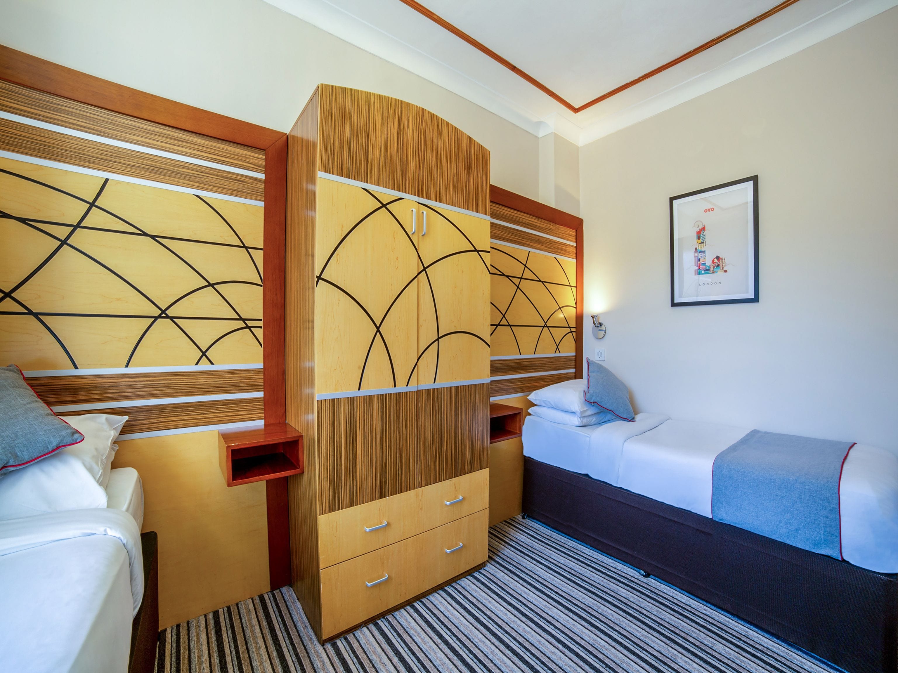 Een hotelkamer met een bed, een bank, een houten garderobe en een lijst met een foto aan de muur.