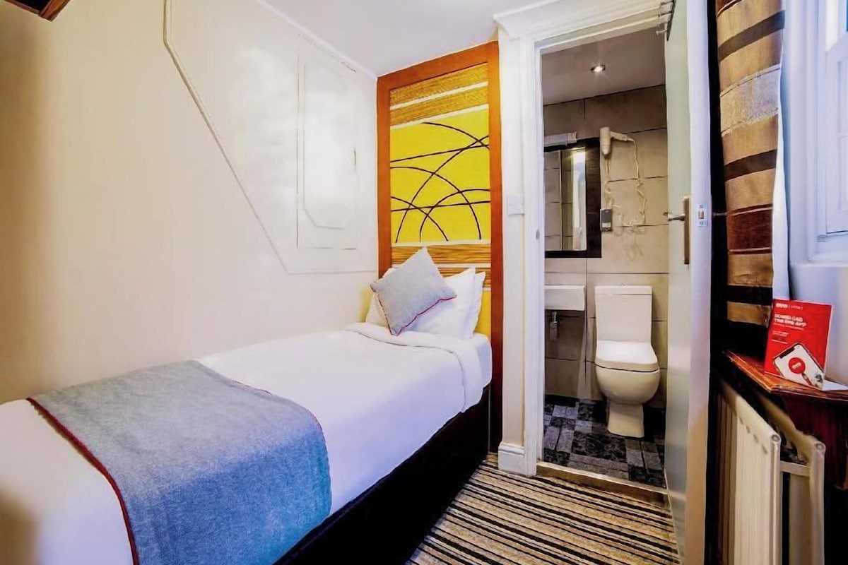 A hotel room with a bed, a bathroom, and a visible shower area.