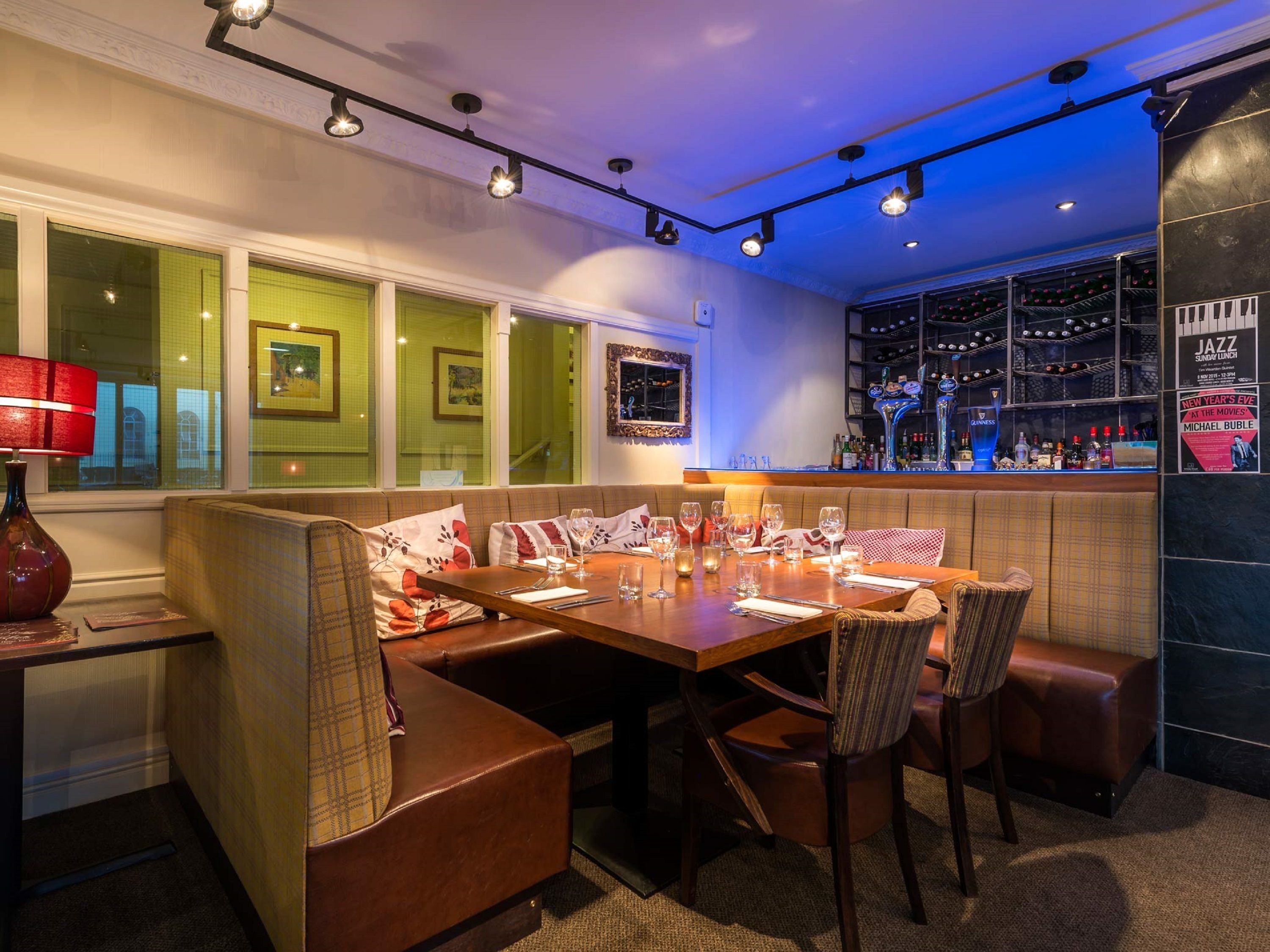 Un restaurante con área de bar, asientos con vistas a la ciudad y un diseño interior moderno.