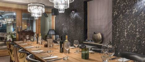 A dining area with a long wooden table set for a meal, surrounded by upholstered chairs.