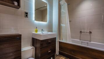 Un baño moderno con un tocador de madera, un lavabo, un espejo y una ducha.