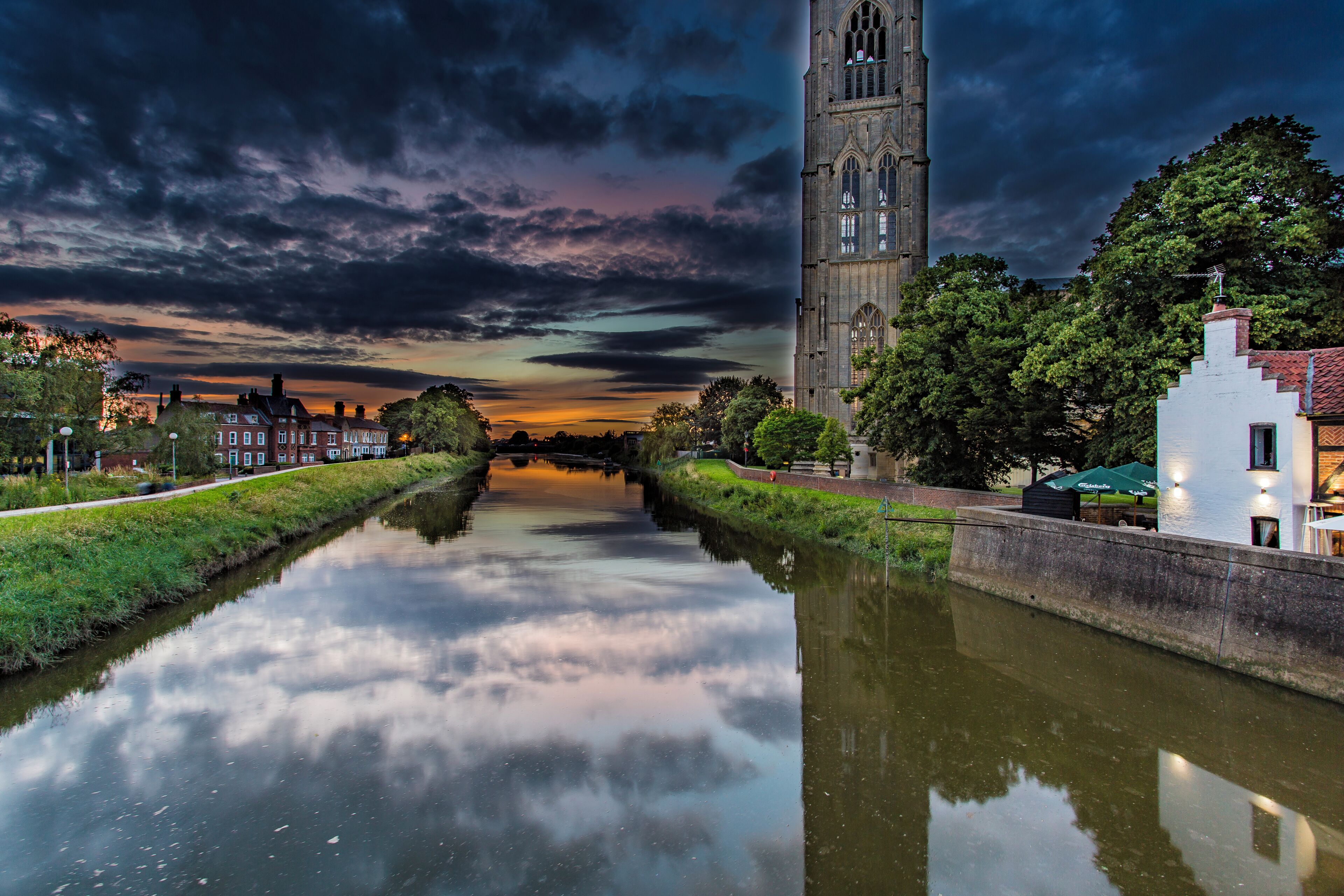 A canal with a tower and buildings in the background.