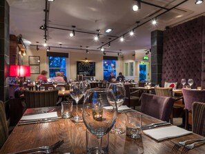 A restaurant interior with wooden tables, clear glassware, and a cozy ambiance.