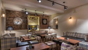 A cozy lounge area with a brick wall, a large mirror, a clock, and a sofa set.