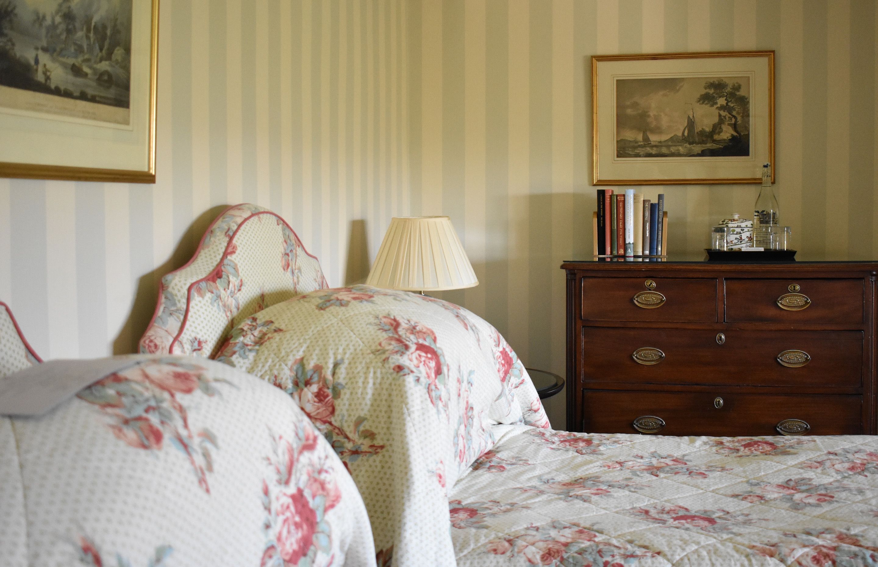 A bedroom with a bed, a dresser, a lamp, and a framed picture on the wall.