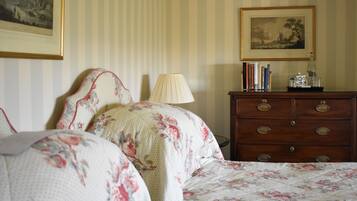 A bedroom with a bed, a dresser, a lamp, and a framed picture on the wall.