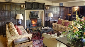 A traditional living room with a fireplace, floral upholstery, and a glass coffee table. - Bodysgallen Hall & Spa (Llandudno)