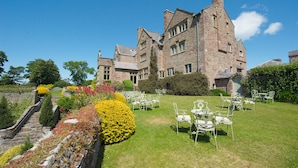 A large stone building with a formal outdoor seating area. - Bodysgallen Hall & Spa (Llandudno)
