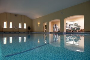Una piscina techada, sillones reclinables de piscina