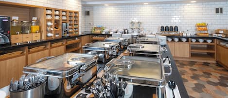 A buffet setup with multiple serving stations, a coffee machine, and a variety of food and drink dispensers.
