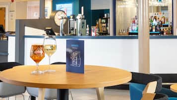 A bar area with a drinks menu, two glasses of beer, and a clock on the wall.