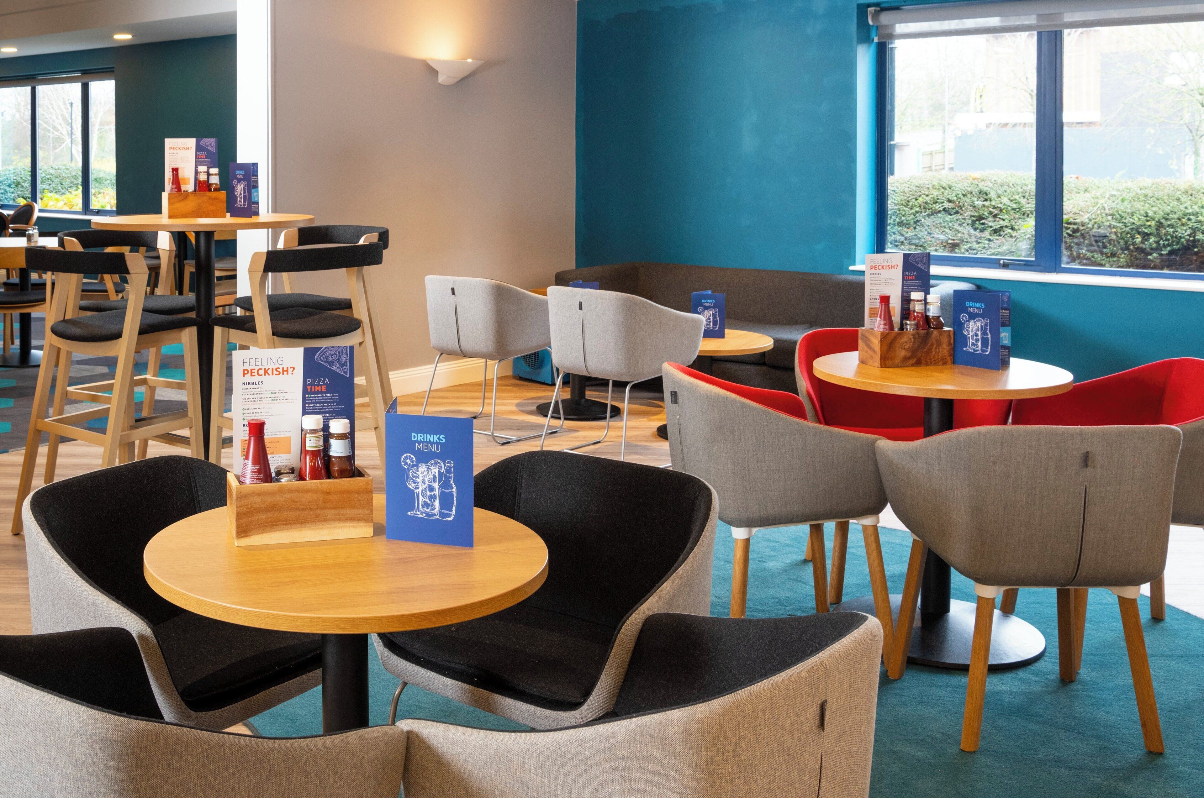 A modern dining area with round tables and chairs, menus, and condiments.