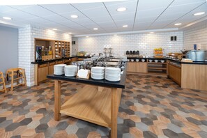 A modern kitchen with white tiled walls, a wooden counter, and a hexagonal patterned floor.