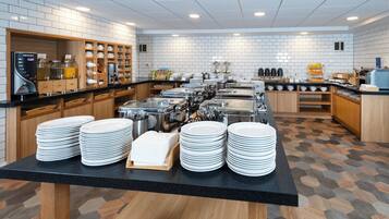 Montaje de bufé con varias estaciones de servicio, una máquina de café y una gran variedad de alimentos.