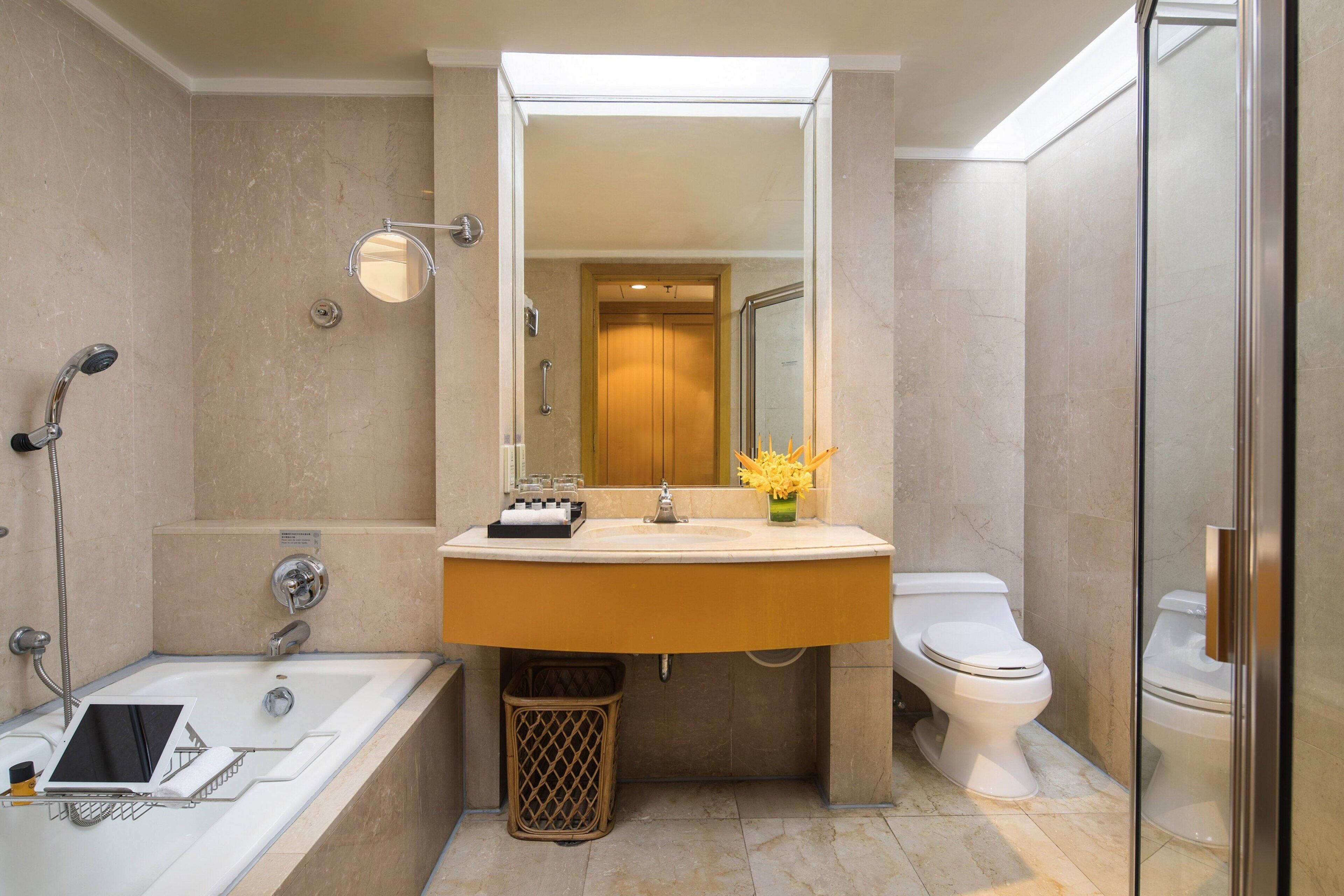 Un baño moderno con bañera, lavamanos, inodoro y ducha con mampara de vidrio.