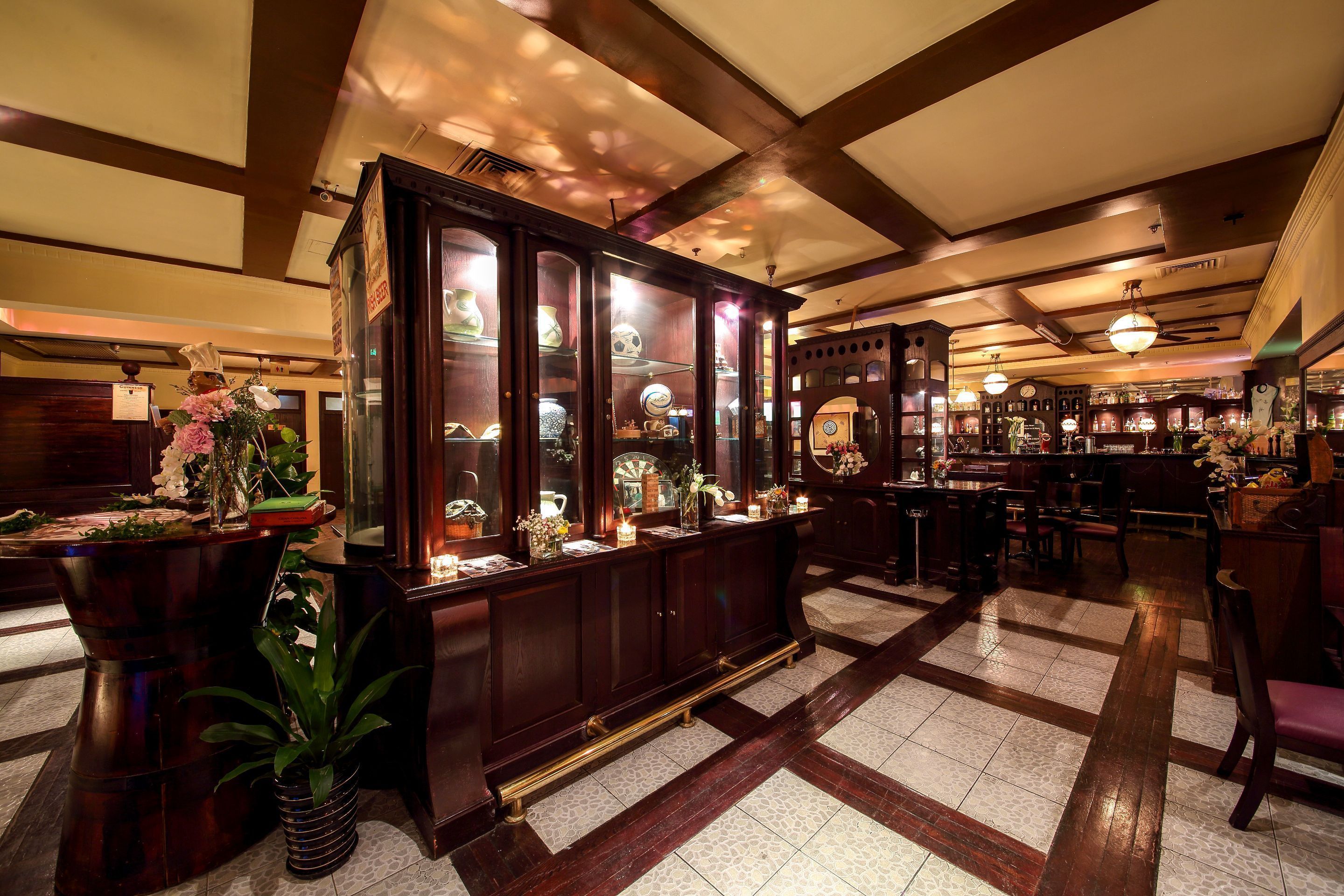 A bar area with wooden cabinets displaying glassware and a large mirror.