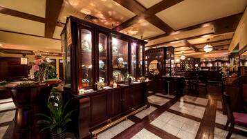 A bar area with wooden cabinets displaying glassware and a large mirror.