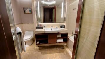 A modern bathroom with a marble floor, a large mirror, a toilet, and a sink with a vanity.