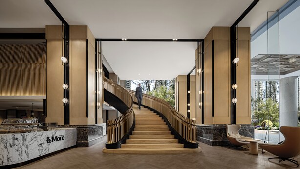 A modern hotel lobby with a marble reception desk, a wooden staircase, and a seating area with a view of the outdoors. - Sheraton Nanjing Kingsley Hotel (Nanjing)