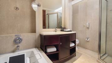 A bathroom with a bathtub, a vanity with a mirror, a toilet, and a shower area.