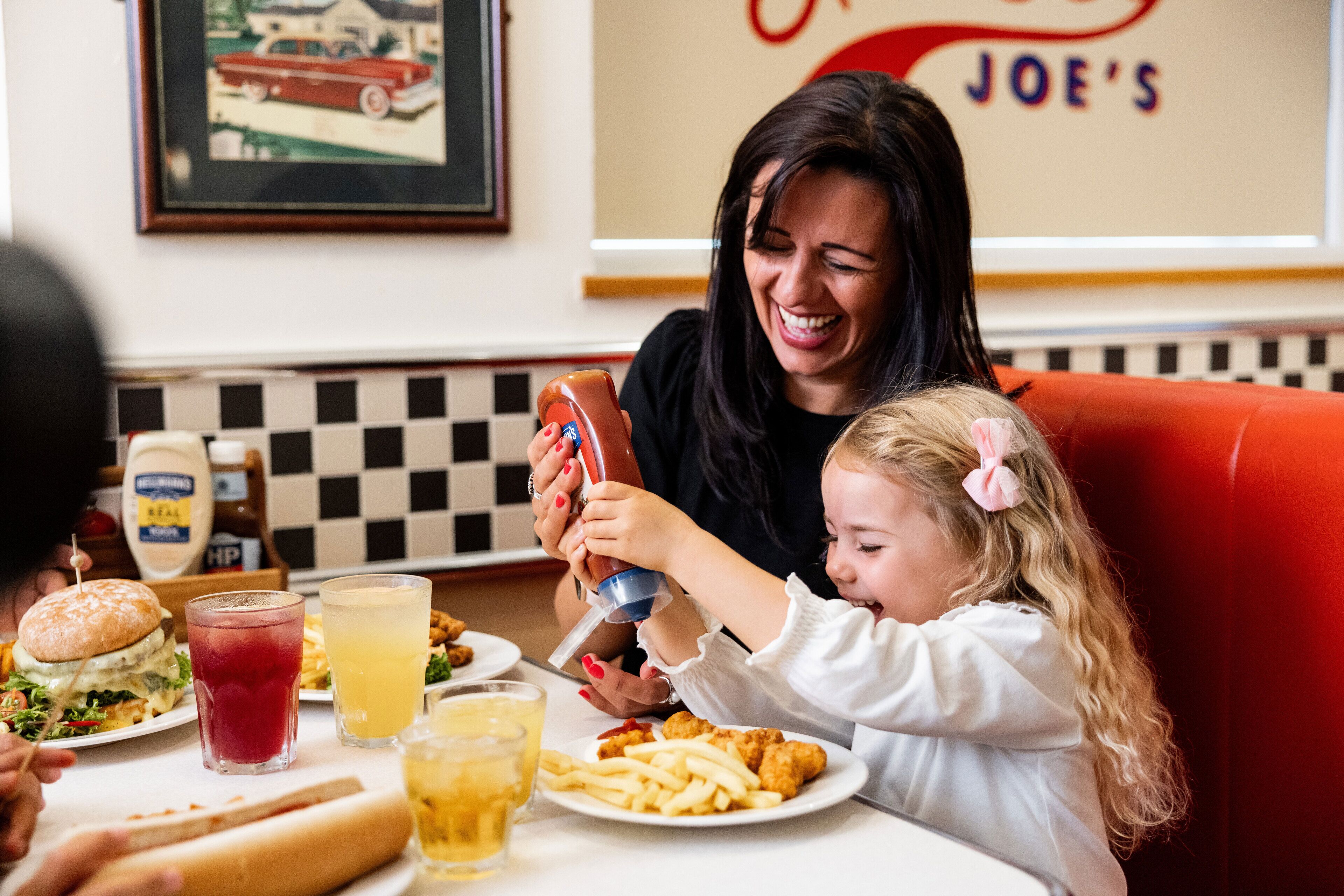 A diner setting with a burger, fries, and drinks on the table.