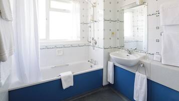 A bathroom with a bathtub, a sink, and a mirror.