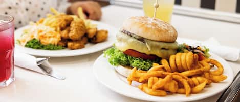 Comida que incluye una hamburguesa, papas fritas y una bebida sobre una mesa.